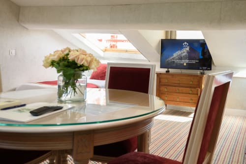 Suite lussuosa dell'Hotel Splendid Cannes con elegante scrivania curva, fiori freschi, TV a schermo piatto e cassettone in legno