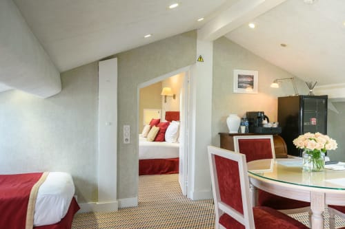 Suite familiare dell'Hotel Splendid Cannes con camera da letto, zona living, sedie in velluto rosso e fiori freschi sulla scrivania