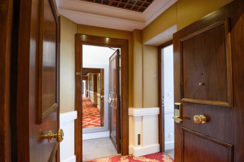 Elegante corridoio nella suite dell'Hotel Splendid Cannes con porte in legno, hardware dorato e moquette rossa decorata