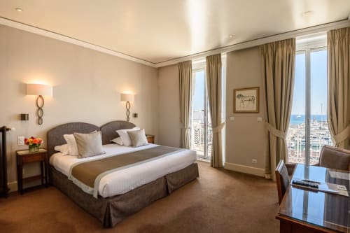 Suite di lusso presso l'Hotel Splendid Cannes con vista sul porto, letto king, arredamenti eleganti e balcone fronte mare