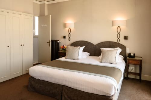 Elegante camera suite all'Hotel Splendid Cannes con letto queen, comodini doppi, lampade moderne e armadio bianco