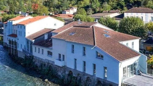Hôtel Maison Du Haut Salat à Seix avec terrasse au bord de l'eau, façade bleue et toit en tuiles rouges