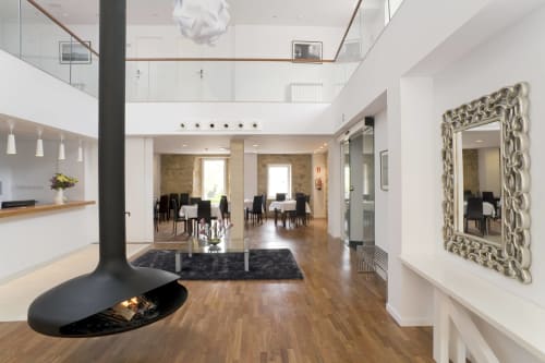 Moderno vestíbulo del Hostal Doña Blanca en España con chimenea suspendida, espejo ornamentado y zona de comedor