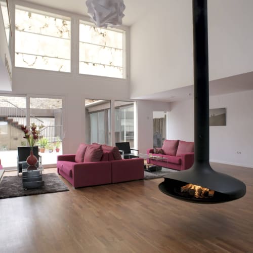 Moderno salón de hotel con sofás rosa, chimenea y techos altos en Hostal Dona Blanca, España