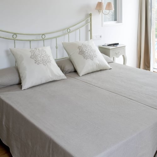Dormitorio elegante en Hostal Doña Blanca con cabecero metálico verde salvia, almohadas blancas y ropa de cama neutra en España.