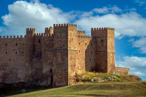 Fortaleza medieval de Sigüenza con torres de piedra y almenas bajo cielo azul