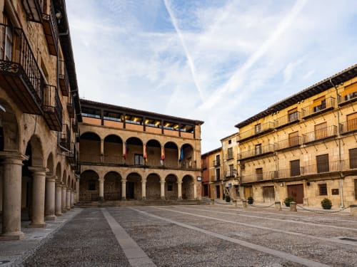 Plaza histórica del Hostal Doña Blanca en Sigüenza, España con edificios porticados y patio de piedra