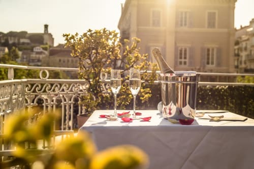Allestimento romantico con champagne sulla terrazza con vista su Cannes, flute, petali di rosa e tramonto sulla città
