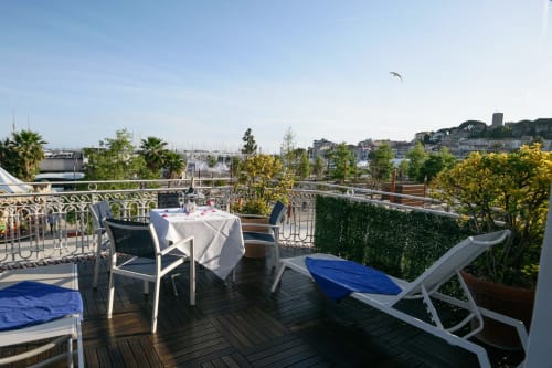 Terrazza della camera Hotel Splendid Cannes con tavolo da pranzo, lettini e vista panoramica sul porto di Cannes