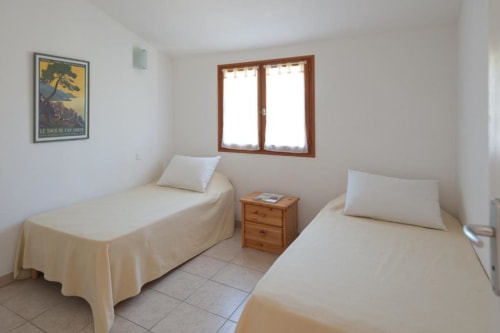 Chambre double lumineuse avec deux lits simples, table de nuit en bois et vue sur le jardin à la villa Casa Callista Est
