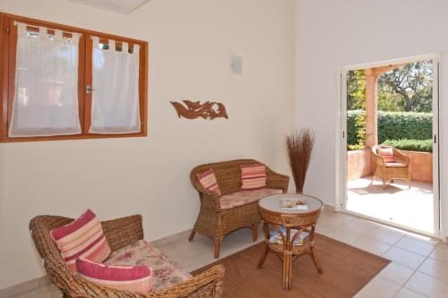 Salon confortable avec mobilier en rotin, coussins rayés et vue sur le jardin de la villa Casa Callista Est