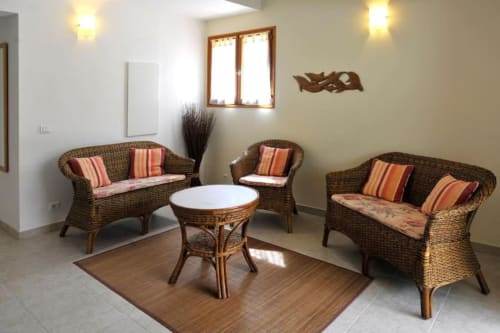 Coin détente en rotin avec coussins rayés et table ronde dans la villa Casa Callista Est de RJD Conciergerie Côte d'Azur