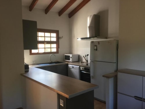 Cuisine contemporaine de la Villa Casa Callista avec appareils en acier inoxydable, plans de travail sombres, poutres en bois et vue sur le jardin