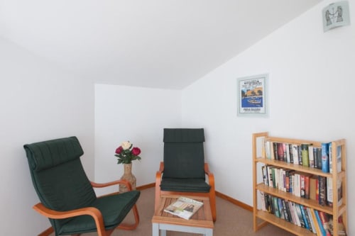 Salon moderne avec mobilier vert et orange, bibliothèque et œuvres encadrées à la villa Casa Callista Est de RJD