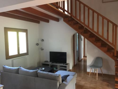 Salon contemporain avec canapé gris, téléviseur, escalier en bois et vue sur le jardin à RJD Conciergerie