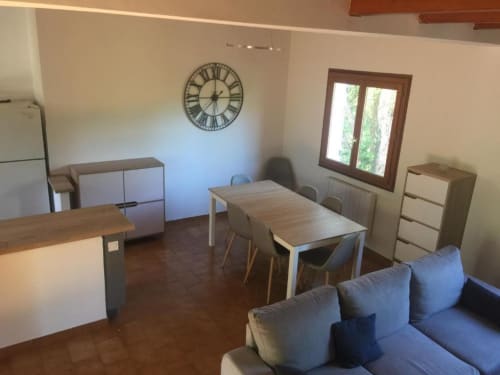 Séjour ouvert avec table à manger, canapé bleu, horloge murale et vue sur le jardin à Villa Casa Callista