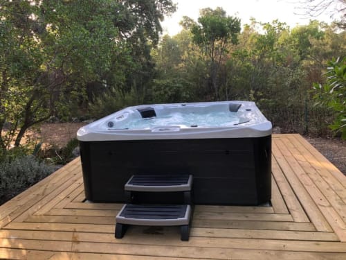 Spa blanc et noir avec escaliers sur terrasse en bois, entouré d'un jardin luxuriant à Villa Casa Callista,