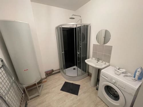 Salle de bains moderne de l'appartement Business Apparts Caudry avec douche, lavabo, machine à laver et chauffe-eau