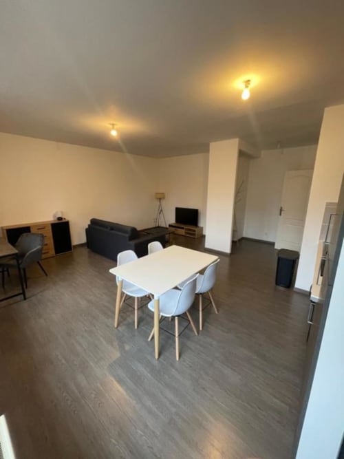 Appartement moderne ouvert chez Business Apparts Caudry avec table à manger, canapé, bureau et cuisine équipée