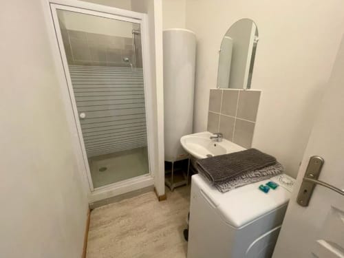 Salle de bain de l'appartement Business Apparts Caudry avec douche, lavabo, machine à laver et miroir