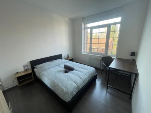 Chambre spacieuse aux Business Apparts Caudry avec lit queen-size, bureau, vue sur la ville et mobilier moderne