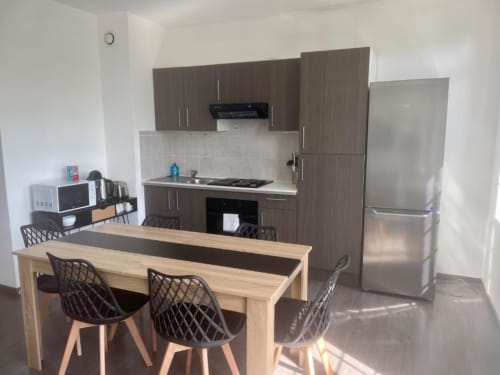 Cuisine moderne et coin repas dans appartement 2 chambres de Business Apparts Caudry avec îlot bois et électroménagers inox