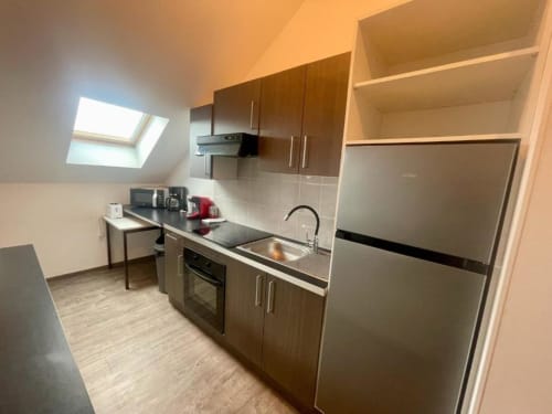 Cuisine moderne dans l'appartement 2 chambres de Business Apparts Caudry avec électroménagers inox, placards sombres et puits de lumière