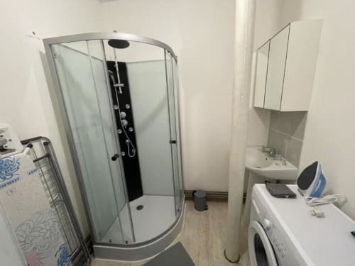 Salle de bains moderne de l'appartement Business Apparts Caudry avec douche à paroi courbe et lavabo blanc