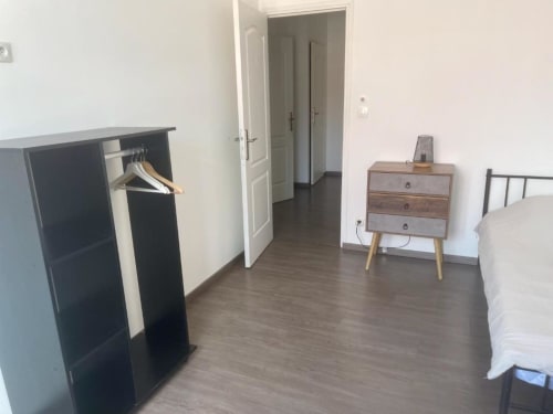 Chambre moderne de l'appartement Business Apparts Caudry avec parquet, lit, table de nuit, armoire et accès ouvert