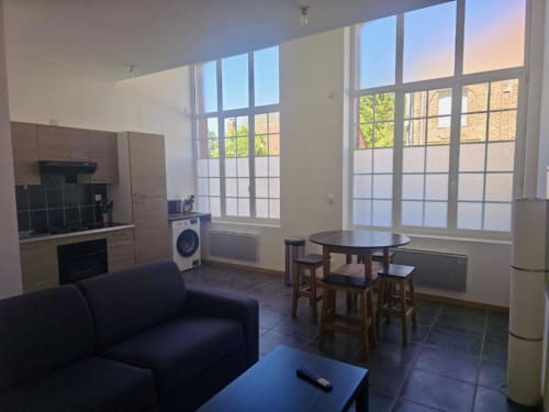 Appartement rez-de-chaussée à Business Apparts Caudry avec séjour ouvert, cuisine, salle à manger et vue sur la ville par grandes baies