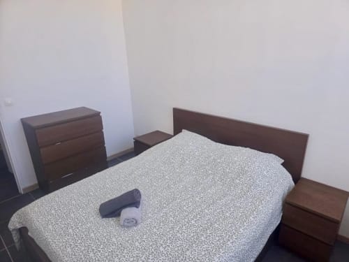 Chambre dans l'appartement Business Apparts Caudry avec lit queen-size, meubles en bois foncé et literie à motifs clairs