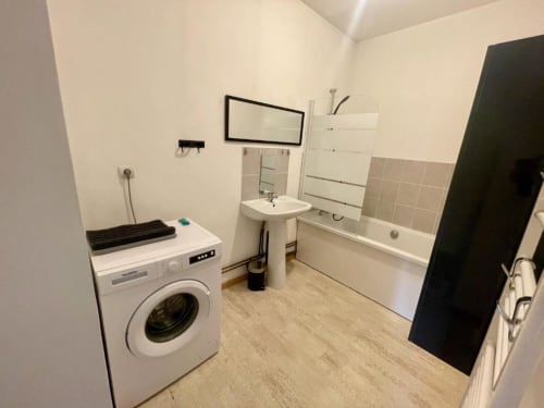 Salle de bain moderne avec lave-linge, lavabo sur colonne et baignoire à l'appartement Business Apparts Caudry en France