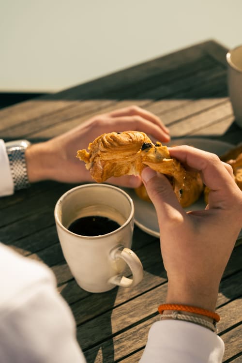 Client dégustant une pâtisserie et un café à la terrasse du gîte La Maison du Potier, Valras-Plage