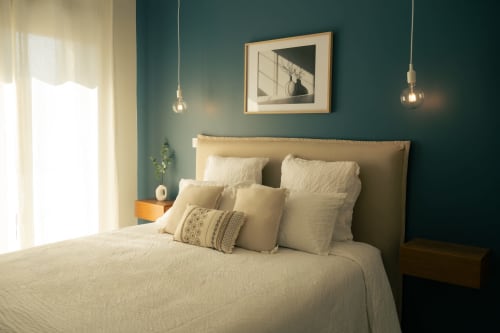 Chambre élégante à La Maison du Potier à Valras-Plage avec murs bleu-vert, literie crème et luminaires suspendus