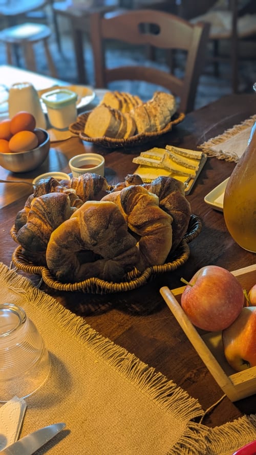 Colazione Casa Orma con cornetti freschi, frutta e bevande su tavolo in legno a Saint-Ilpize