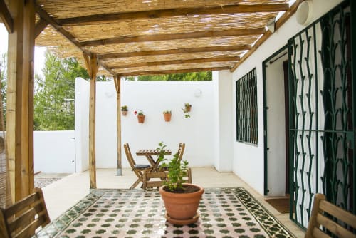 Covered patio at B&B Masía Aitona in Les Useres with wooden pergola, terracotta pots, and traditional tile flooring