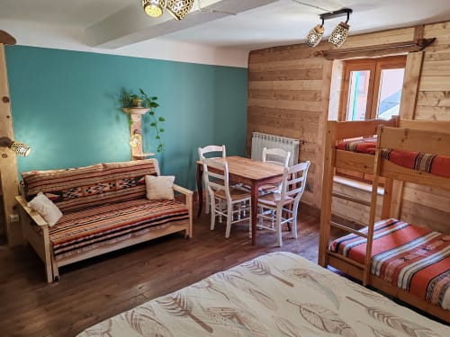 Spacieuse chambre familiale à La Petite étoile D'hôtes avec mobilier en bois, mur d'accent turquoise, lits superposés et coin repas