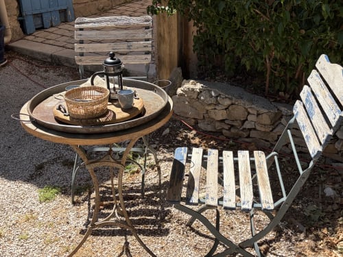 Espace de détente au Patio aux Oiseaux avec table ronde, lanterne et chaises en bois patinées surplombant La Ciotat