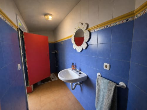 Modern bathroom at Casa Señorial Sasueta in San Sebastián with blue tiles, round mirror, and white sink