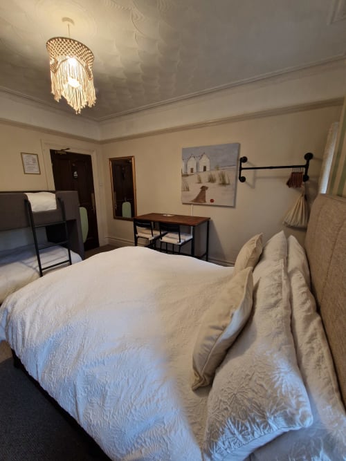 Spacious family bedroom at Blacksheep Lodge in Holyhead with white bedding, desk, bunk beds, and pendant lighting