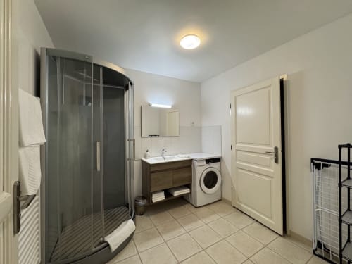 Salle de bain moderne à l'Appartement Foix au Domaine de Bize, Mirepoix, avec douche, vasque, machine à laver et sèche-serviettes chauffant