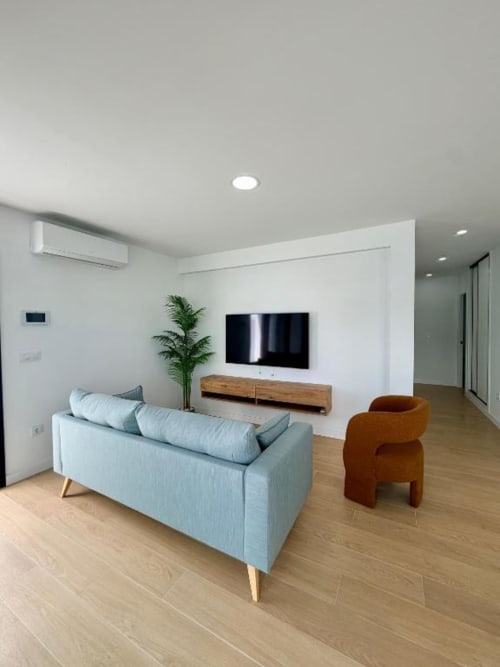 Elegante sala de estar en Villa Rua C de Barrosa Home con sofá azul claro, televisor de pantalla plana, silla terracota y suelos de madera