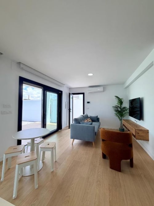 Sala de estar moderna en Villa Rua C, Chiclana de Barrosa Home, con sofá gris, mesa de comedor, TV de pantalla plana y acceso a terraza