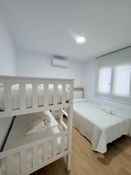 Luminoso dormitorio moderno con cuna blanca y cama en la villa Barrosa Home de Chiclana de la Frontera, España