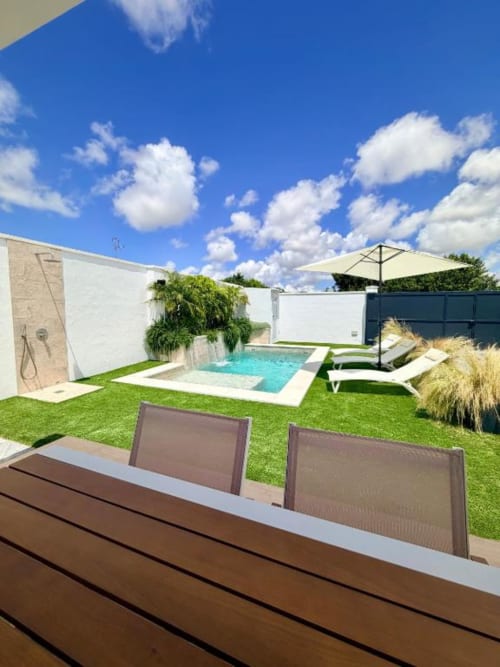 Villa moderna con piscina privada, tumbonas, sombrilla, jardín cuidado, ducha exterior y zona de comedor en Chiclana de la