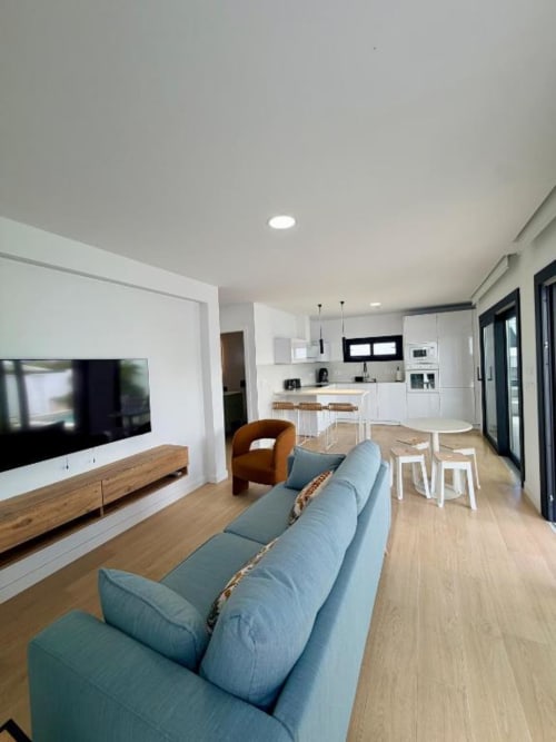 Moderna zona de estar abierta en Villa Rua C, Chiclana de la Frontera, con sofá azul, cocina y comedor