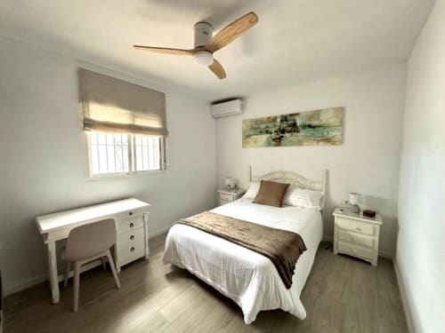 Luminoso dormitorio en Villa Faro de Barrosa Home, Hozanejos, con cama queen, escritorio, ventilador de techo y vista al jardín