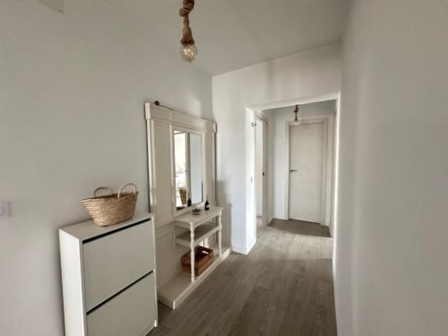 Pasillo moderno en Villa Faro de Barrosa Home con puertas blancas, suelos de madera y mobiliario contemporáneo