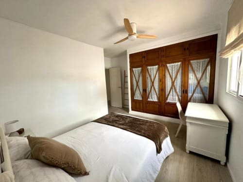 Dormitorio luminoso en Villa Faro de Hozanejos con armario de madera, ventilador de techo y vistas al jardín