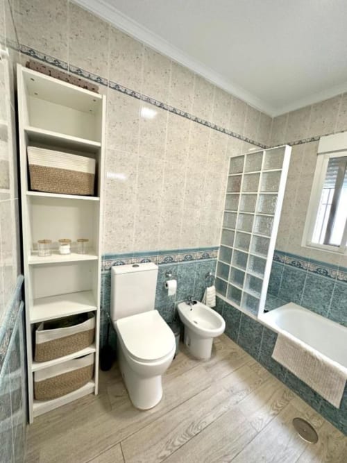 Baño moderno en Villa Faro con inodoro, bidé, bañera, estanterías de almacenamiento y azulejos azul verdoso